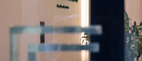 A glass partition with a reflection of a sign that reads "VAULT ATHENS."