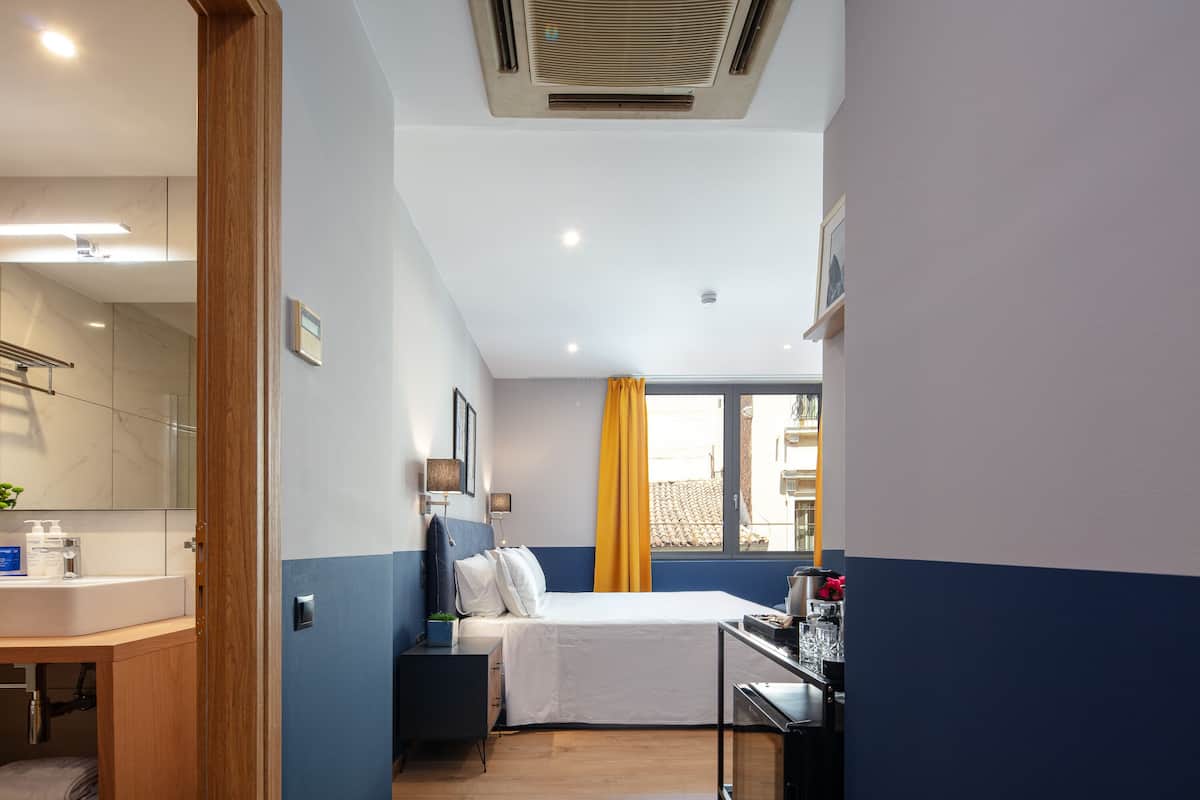 Une chambre d’hôtel avec un lit, une table de chevet et une fenêtre avec des rideaux.