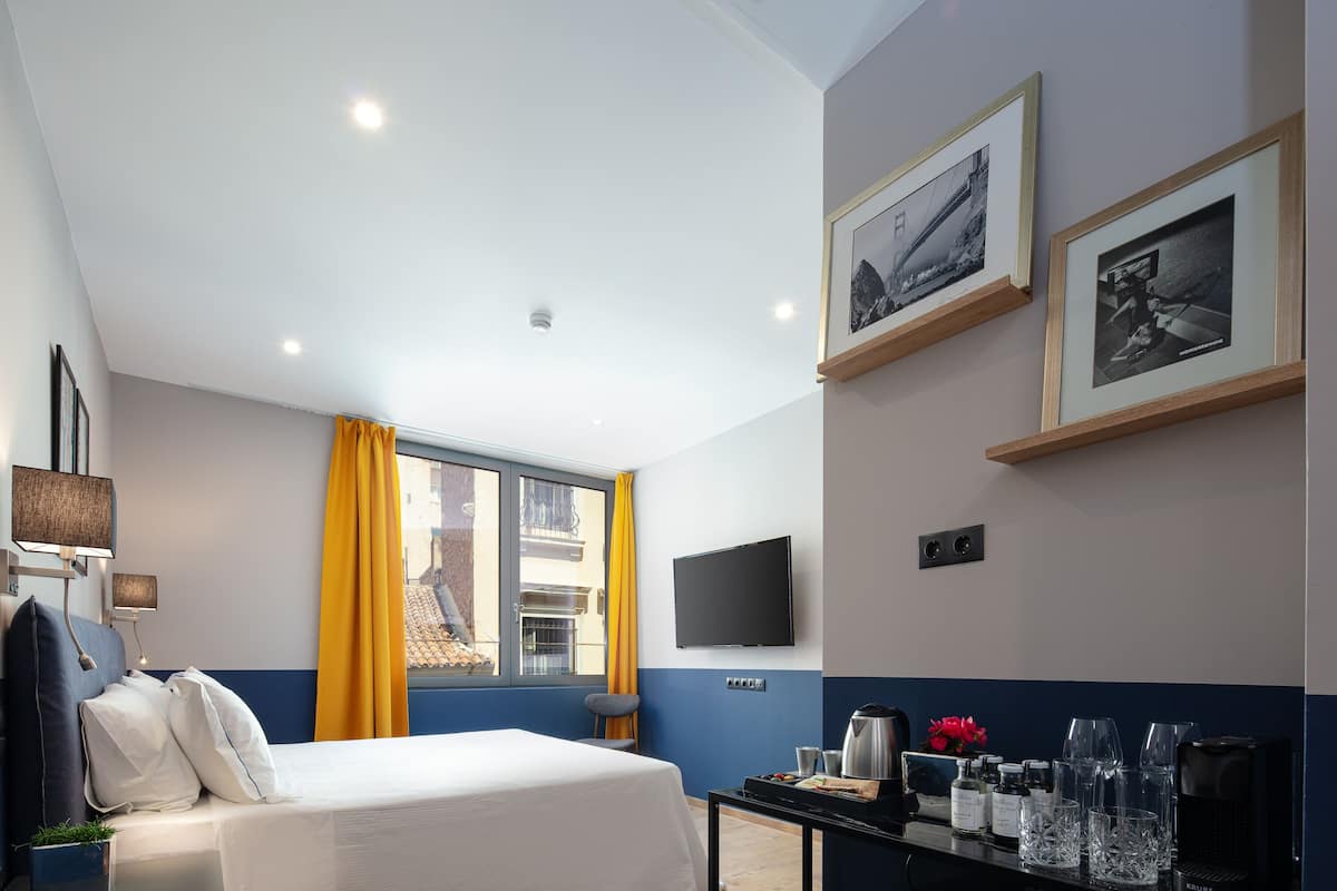 Une chambre d’hôtel avec un lit, une table avec des commodités, une télévision et des tableaux encadrés au mur.