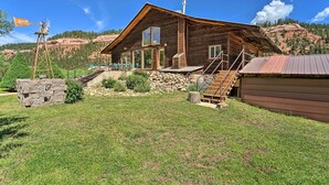 Eine rustikale Holzhütte mit Steinunterbau, einem Windrad und einer Treppe, die zum Eingang führt.