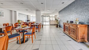 A spacious dining area with wooden tables and chairs, a central buffet, and a patterned wall. - Hôtel Robespierre (Montreuil)