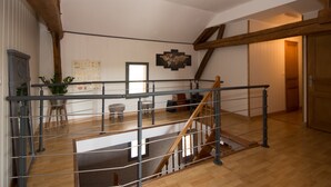 Un loft espacioso con una escalera de madera, barandilla de metal y un mapa mundial en la pared.