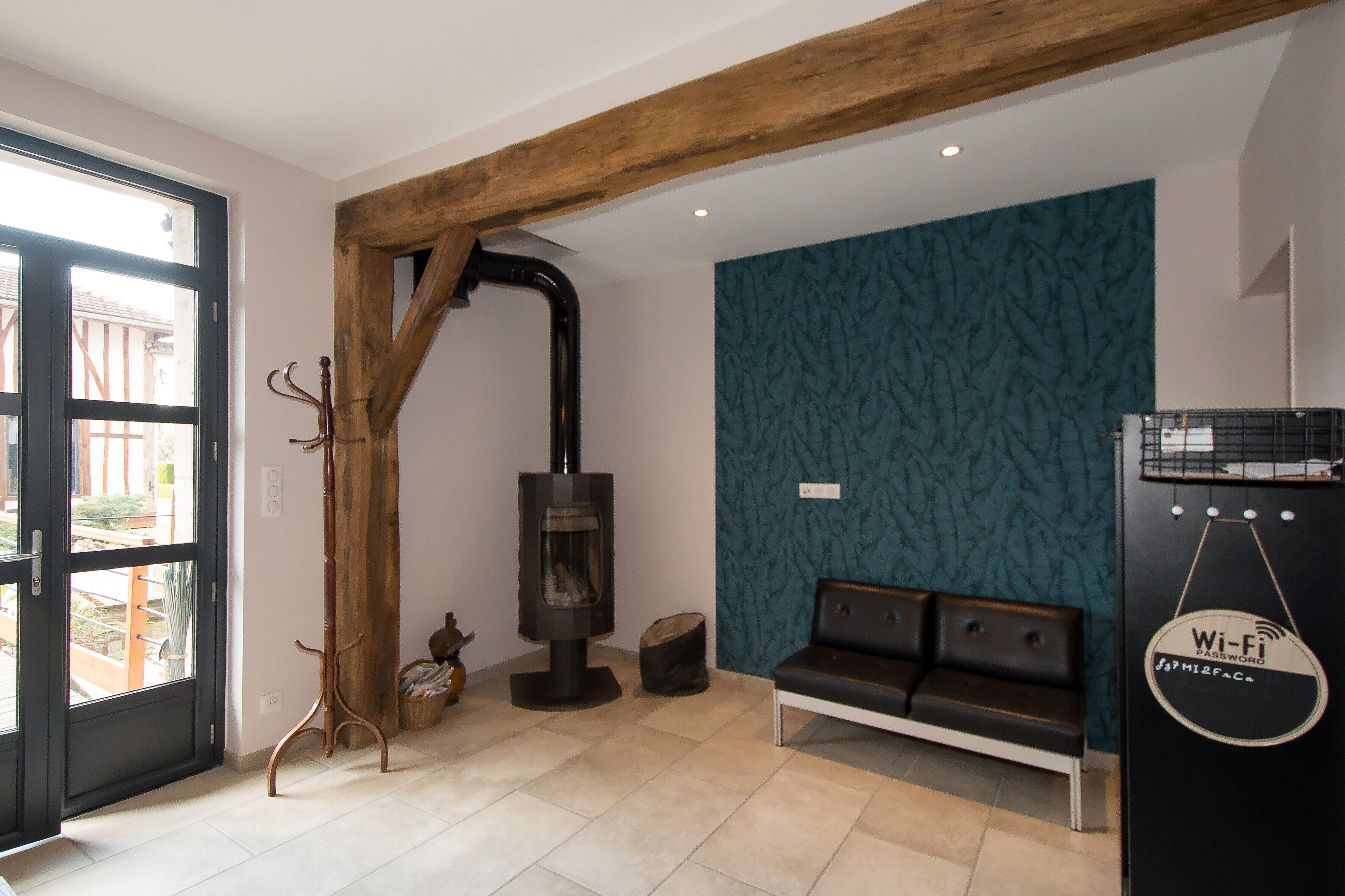 Een modern interieur met een houten balkenplafond, een stenen openhaard, een bankje en een Wi-Fi sign.