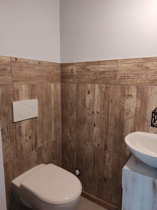 A bathroom with a wooden wall panel, a toilet, and a sink.