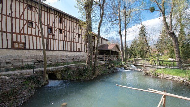 Un edificio tradicional de entramado de madera con un río y un puente de madera.