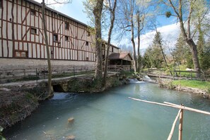 A traditional half-timbered building with a river and wooden bridge.