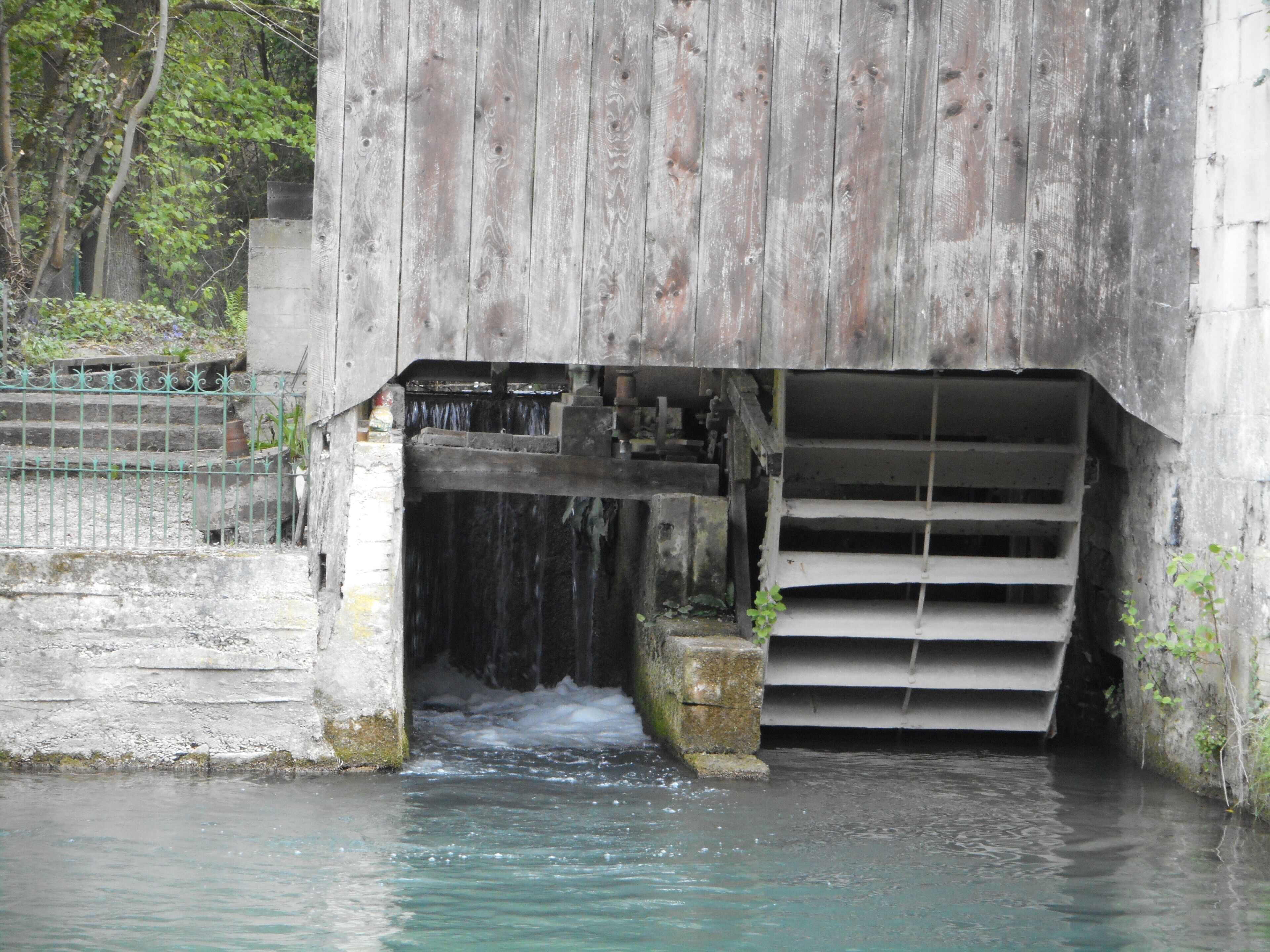 Un pont en béton avec un canal d’eau en dessous, entouré de verdure.