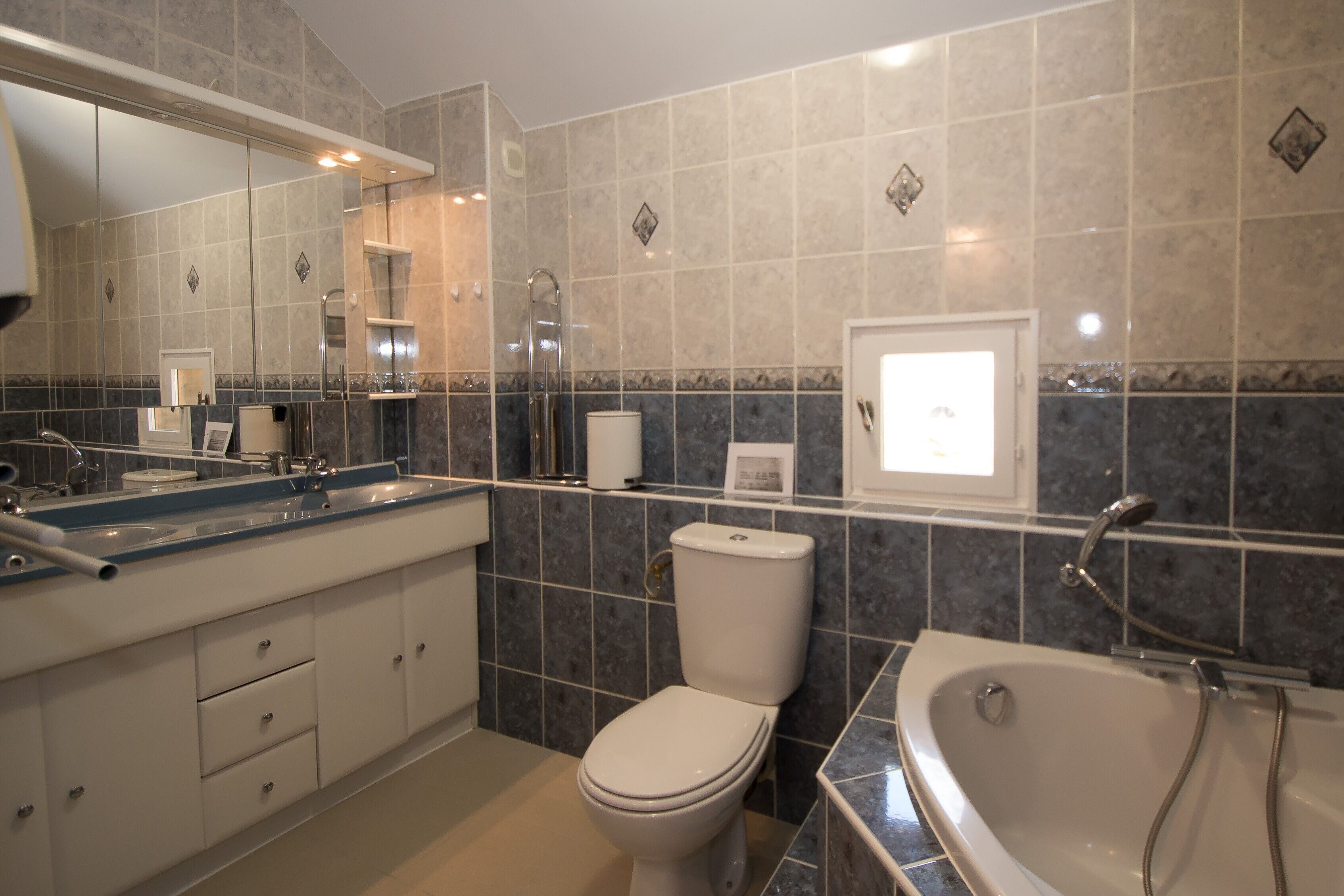 Une salle de bain moderne équipée d’une baignoire, de toilettes et d’un meuble-lavabo.
