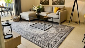 A living room with a sofa, coffee table, patterned rug, artwork, and a floor lamp. - Apartment Lotus 486 with Shared Pool, Terrace & Wi-Fi (LA CALA DE MIJAS)