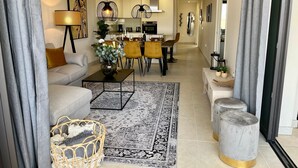 A modern living room with a sofa, coffee table, and a dining area with chairs and a table. - Apartment Lotus 486 with Shared Pool, Terrace & Wi-Fi (LA CALA DE MIJAS)