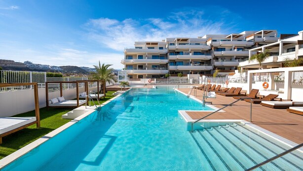 A swimming pool with lounge chairs and a view of a multi-story building. - Apartment Lotus 486 with Shared Pool, Terrace & Wi-Fi (LA CALA DE MIJAS)