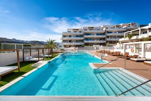A swimming pool with lounge chairs and a view of a multi-story building. - Apartment Lotus 486 with Shared Pool, Terrace & Wi-Fi (LA CALA DE MIJAS)