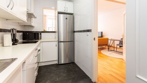 Eine moderne Küche mit weißen Schränken, einem Edelstahlkühlschrank und einer Mikrowelle mit schwarzer Arbeitsplatte.