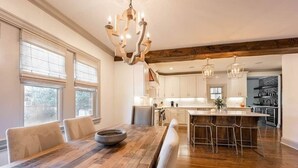 Eine moderne Küche mit Holzboden, einer großen Kochinsel mit Barhocker und einem einzigartigen Kronleuchter.