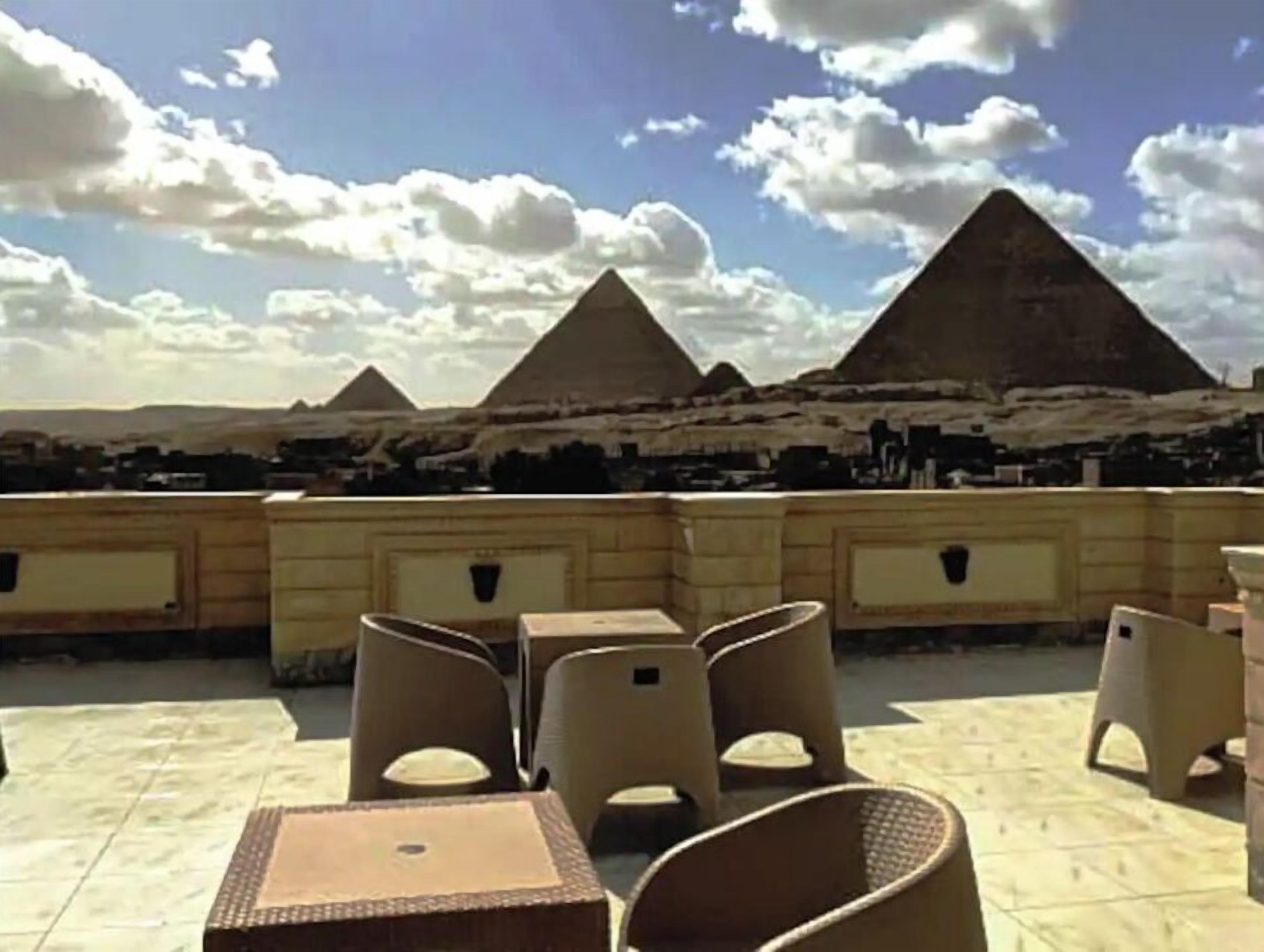 An outdoor seating area with tables and chairs, overlooking the pyramids.