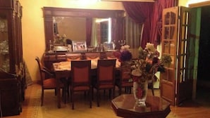A dining room with a wooden table and chairs, a vase with flowers, and a mirror above the table. - pyramids kingdom apartment (الجيزة)