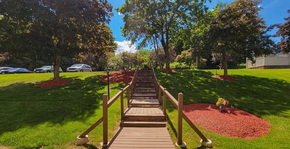 Stroll down the pathway to a serene outdoor space with lush greenery and shaded seating areas.