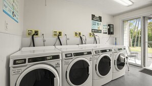 Eine Wäscherei mit vier Maytag Waschmaschinen, einem Schild mit der Aufschrift 'Waschen leicht gemacht' und einer Zahlstation.