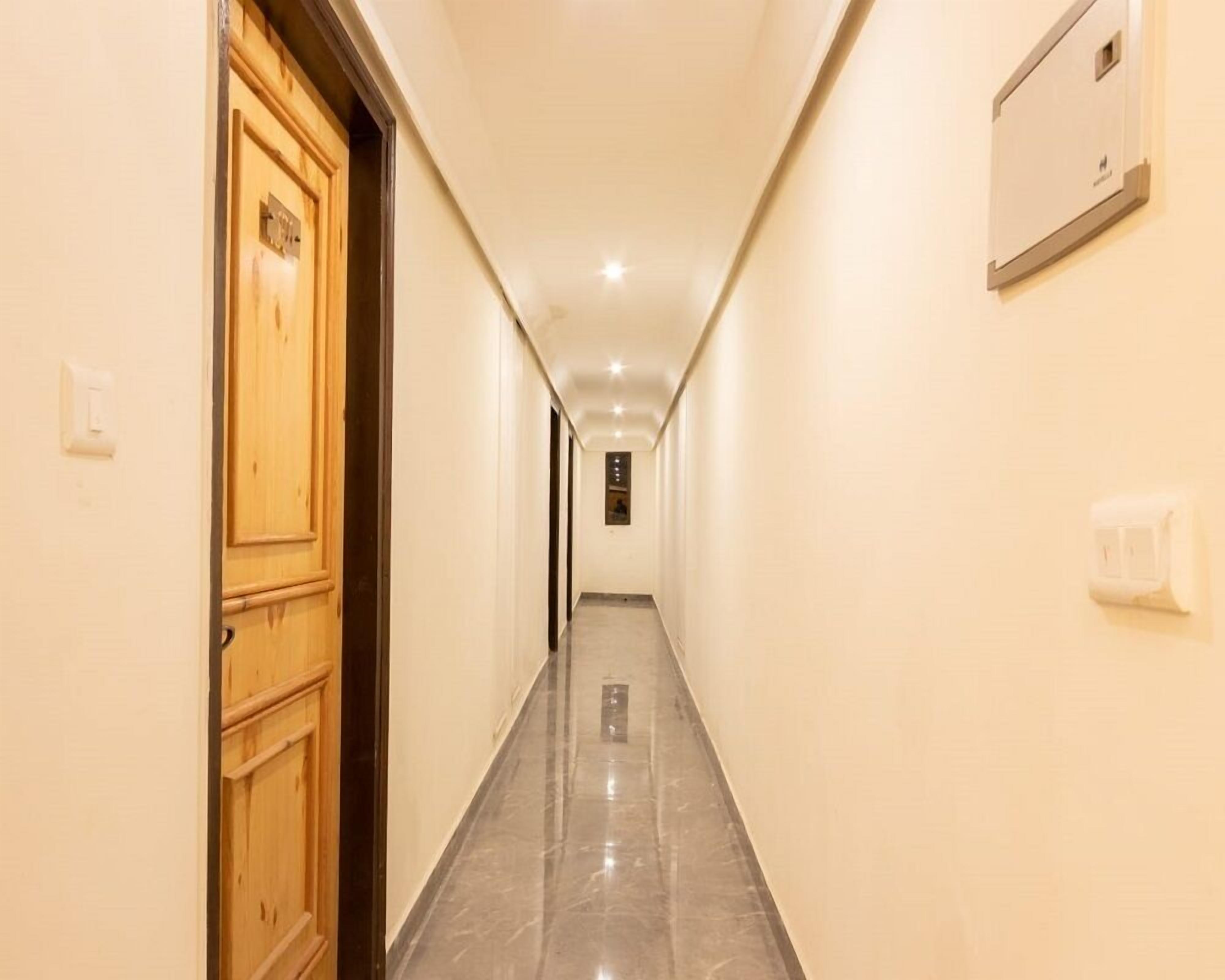 A hallway with wooden doors, a light switch, and a wall-mounted light fixture.