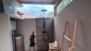 Un espacio al aire libre techado con ducha, una mesa con vela y una planta de cactus.