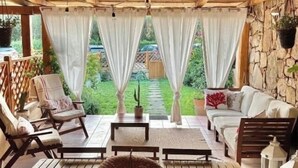 Un área de patio techada con muebles de madera, incluyendo una mesa y sillas, además de un sofá.