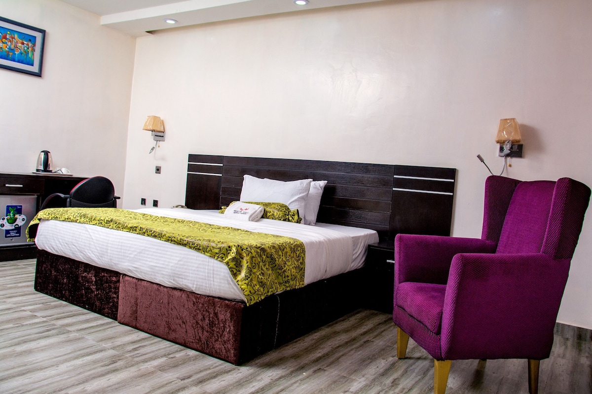 Une chambre d’hôtel comprenant un lit, un bureau, une chaise et deux lampes fixées au mur.