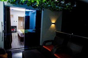 A hotel room with a bed, a small desk, a chair, a sofa, and a wall-mounted light fixture. - Whitevill Hospitality and Homes (Ibadan)