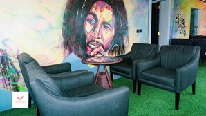 Una habitación con dos sofás de cuero negro, una mesa de mimbre y un mural de colores en la pared.
