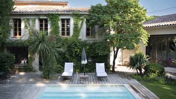 Relax by the serene pool surrounded by lush greenery and traditional architecture.