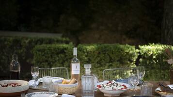 An outdoor dining table set with various dishes, glasses, and a wine bottle.