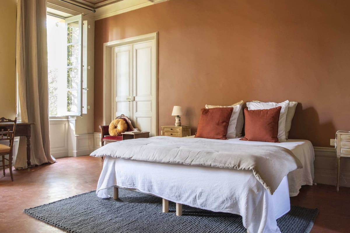 A bedroom with a large bed, a nightstand, a lamp, and a chair.