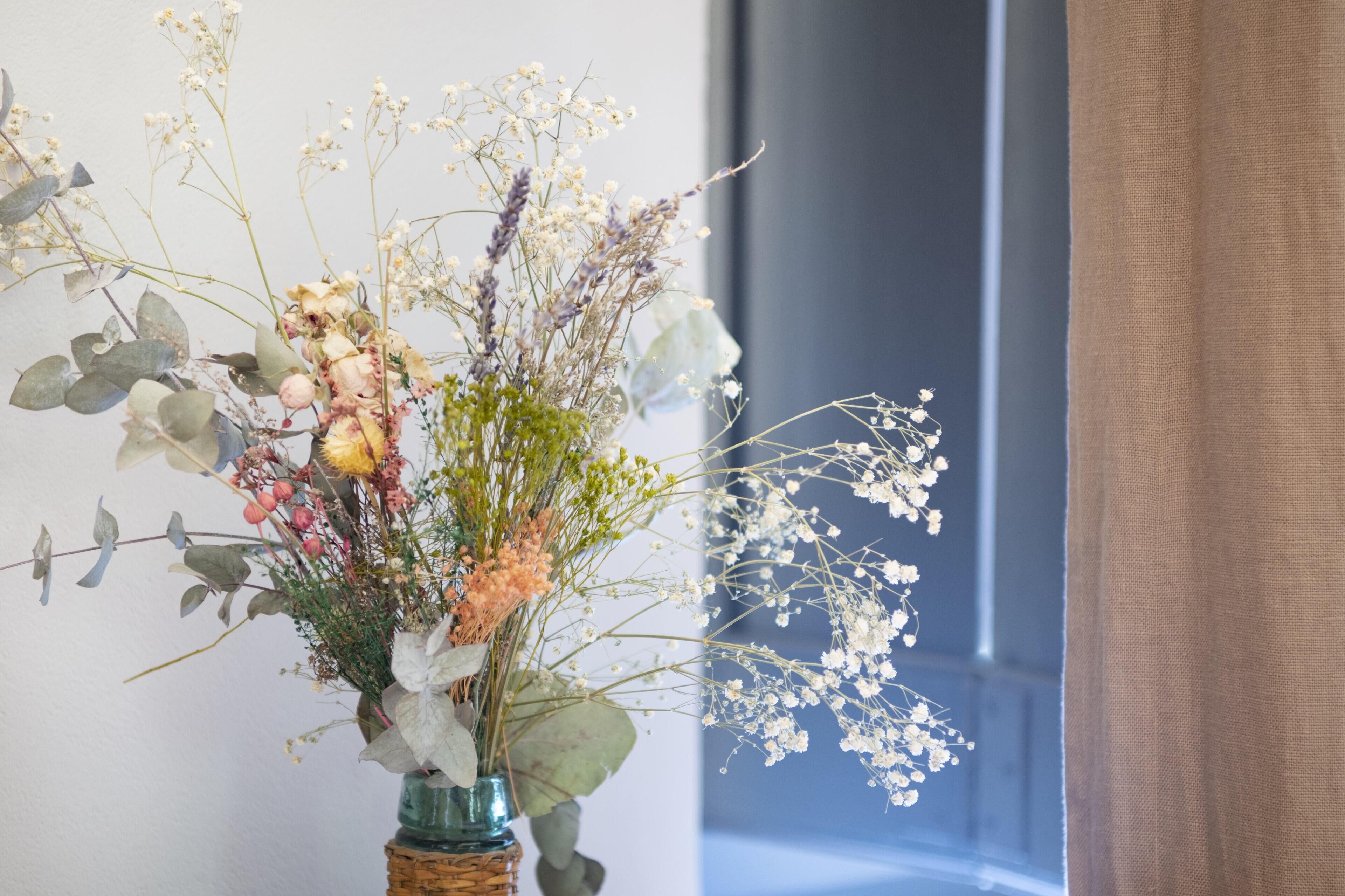 A vase with a floral arrangement of various flowers and leaves.