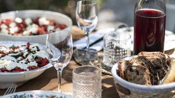A table with a bowl of salad, a bottle of red drink, and slices of bread.