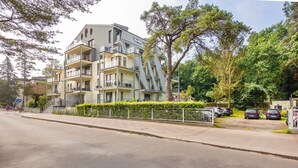 A multi-story residential building with balconies, a gated parking area, and a well-maintained hedge. - Apartamenty Sun&Snow Rezydencja Bursztyn (Swinoujscie)