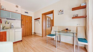 A compact kitchen with a coffee maker, a broom, and a door leading to another room. - Apartamenty Sun&Snow Rezydencja Bursztyn (Swinoujscie)
