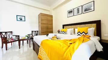 Habitación de hotel con cama, armario de madera, escritorio con silla y una pequeña mesa con planta.