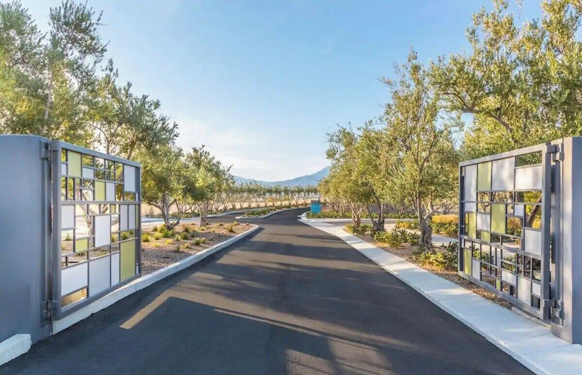 A pathway flanked by modern, glass-paneled structures with a clear view of a mountainous landscape in the distance.