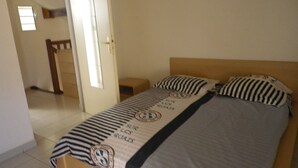 A bedroom with a bed, a wooden headboard, and a striped blanket. - Corail de l Ermitage Duplex T3 5mn beach (Saint Paul)