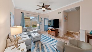 Ein Wohnzimmer mit einer Couch, einem Fernseher und einem Deckenventilator.