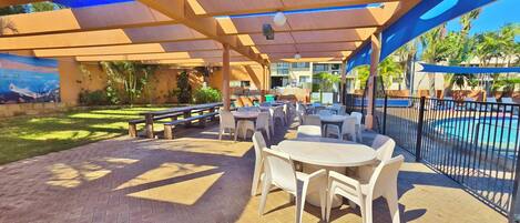 An outdoor patio with tables and chairs, a pool, and a mural.