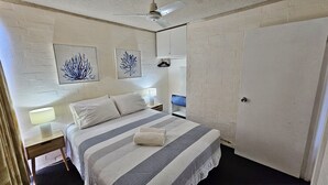 A bedroom with a bed, two wall-mounted lamps, a ceiling fan, and two framed wall art pieces. - Riverview Holiday Apartment 32 - Ground Floor -  Kalbarri WA (KALBARRI)