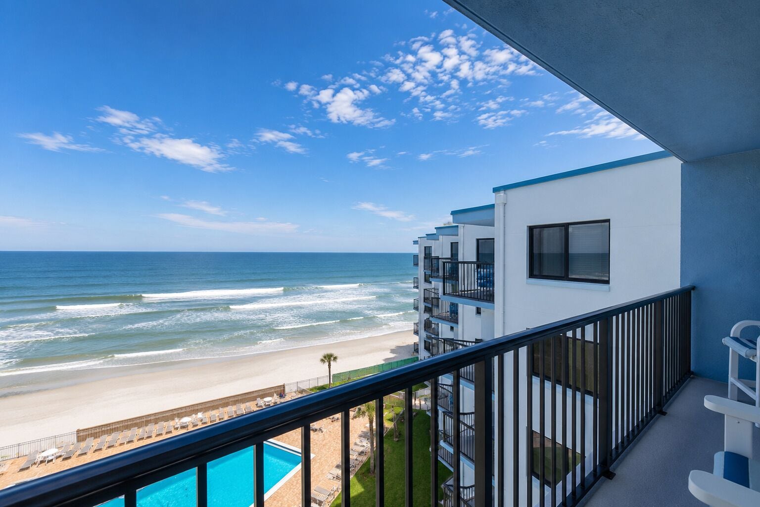 Hotel aan het strand met balkon, zwembad en uitzicht op de oceaan.