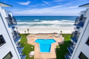 A hotel with a pool, beach view, and multiple balconies. - Top Floor Oceanfront 1BR with Sweeping Ocean Views and Private Balcony (New Smyrna Beach)
