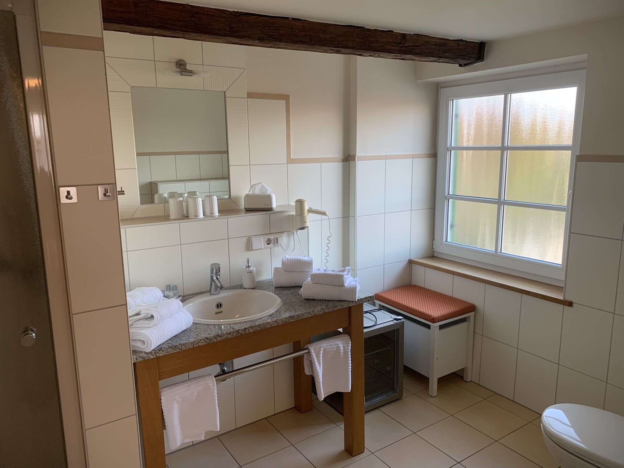A bathroom with a sink, mirror, towel rack, and a window.