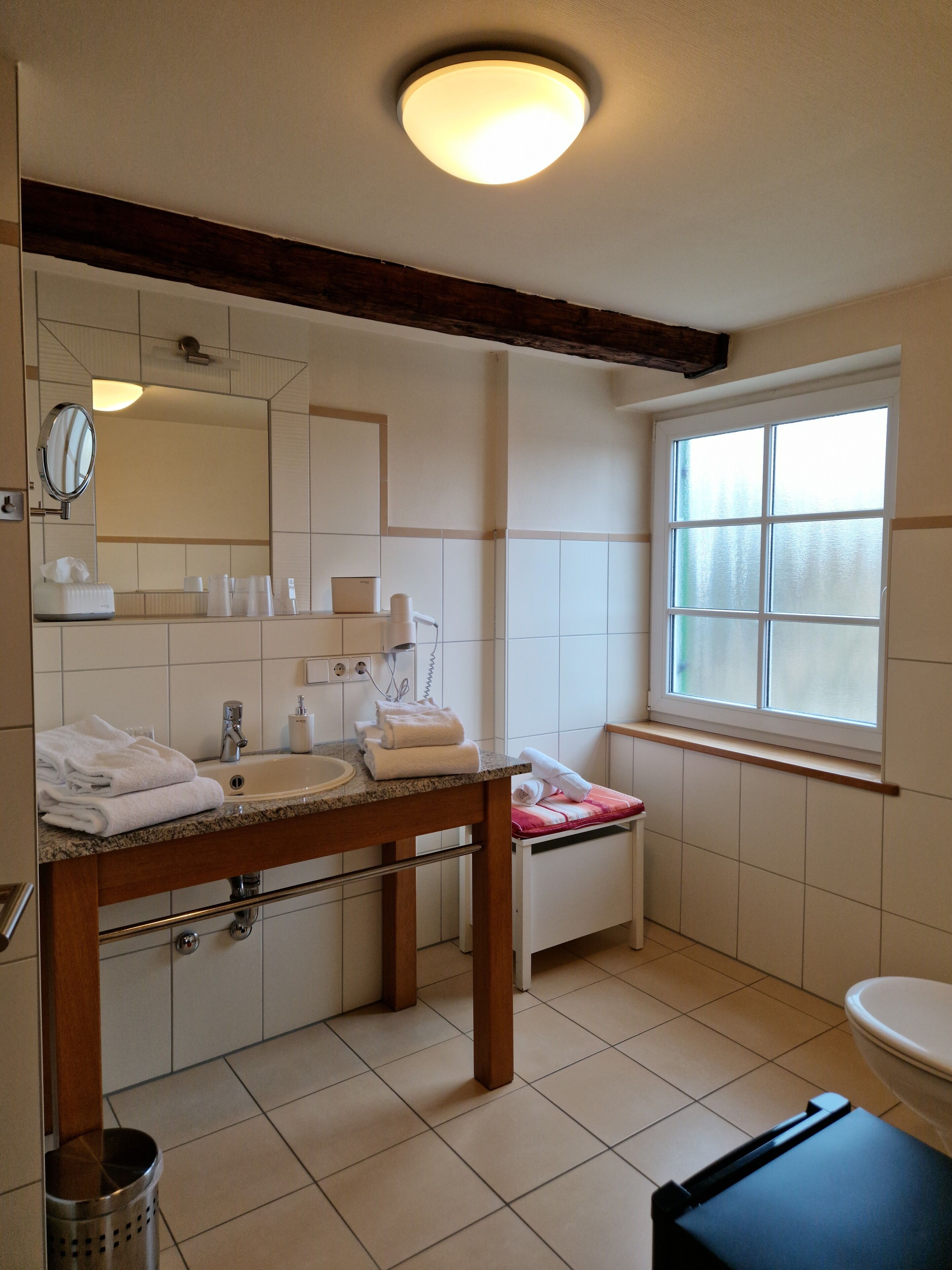 A bathroom with a sink, mirror, and window.