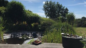 A wooden deck with a view of a garden and a pond.