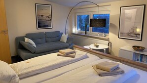 A hotel room with a bed, a sofa, a small table, and a window with a view of the outside.