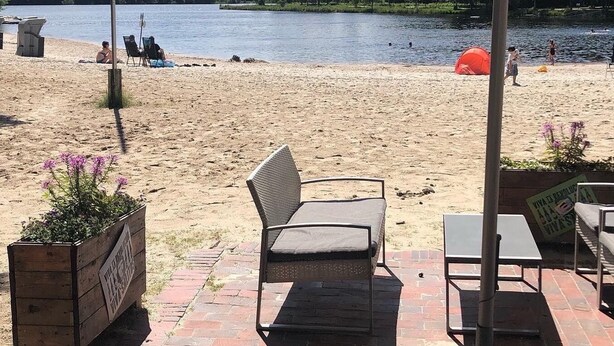 A beach with a wooden deck, chairs, and a sign indicating a wildlife viewing area.