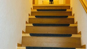 A wooden staircase with a handrail and a small chair at the top.