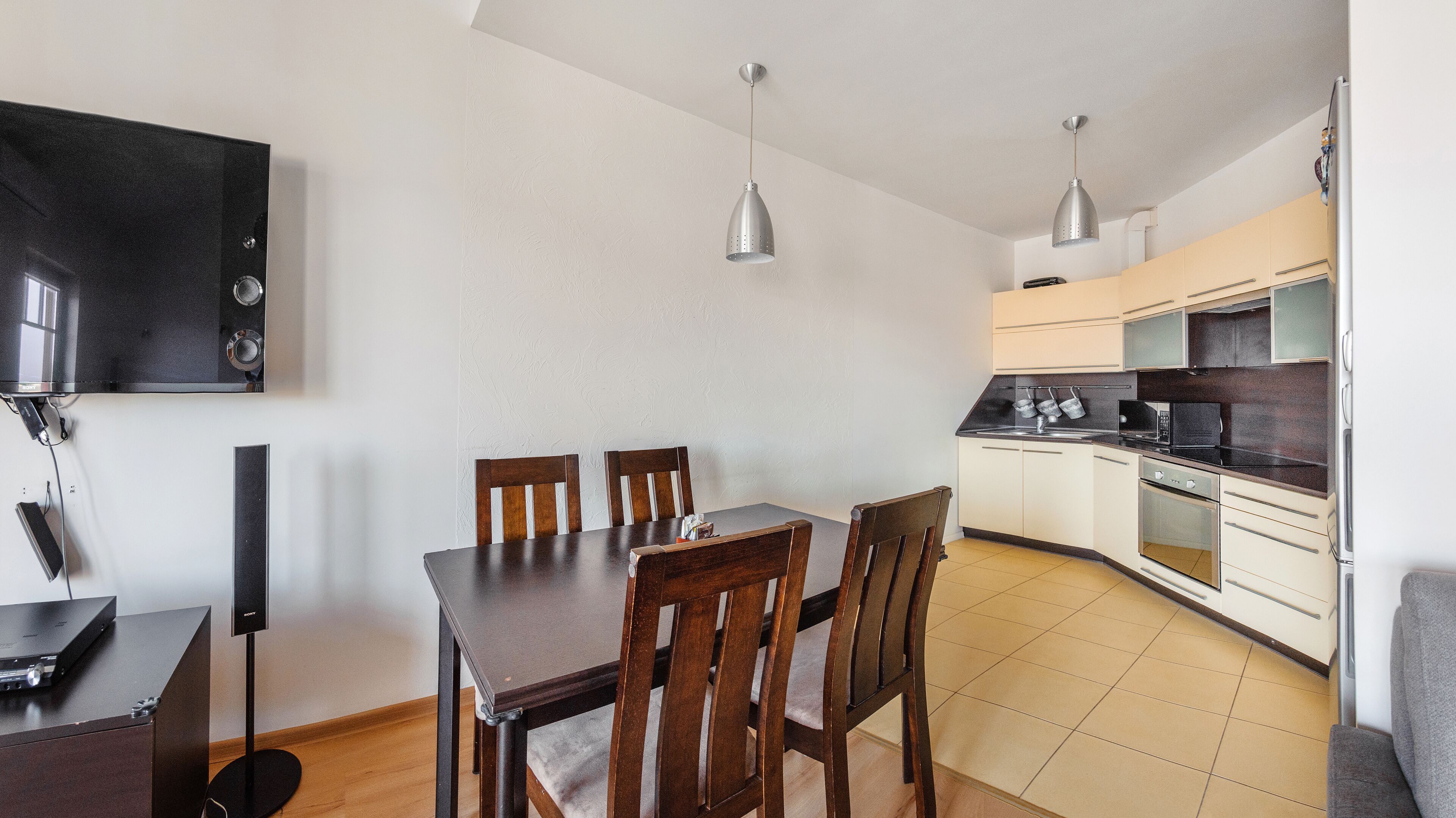 Una cocina moderna con armarios blancos, encimera negra y comedor con sillas de madera.